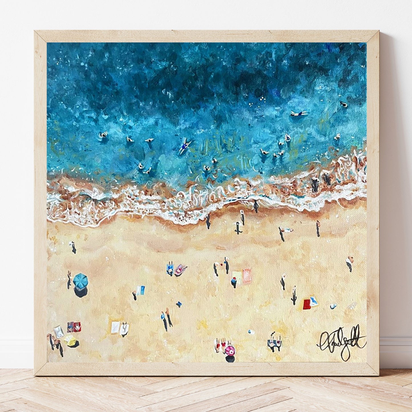 A fine art print of an original acrylic painting of a birds eye view of a beach scene, with turquoise ocean and pale sand, and lots of beach goers relaxing.